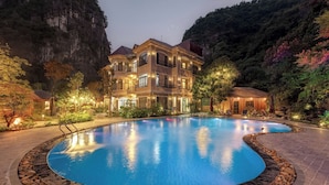 A luxurious hotel with a large swimming pool, surrounded by a landscaped garden and a mountainous backdrop. - Indochine Boutique Hotel Ninh Binh (Nam Hoa Lu)