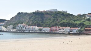 Eine Küstenstadt mit Gebäuden an einem Hügel, einem Sandstrand und ruhiger See.