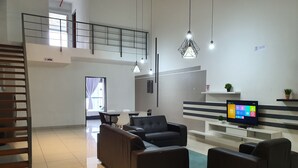 A modern living room with a sofa set, a TV, and a staircase.