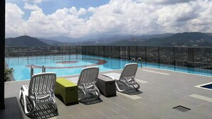 A rooftop pool with lounge chairs and a view of distant mountains.