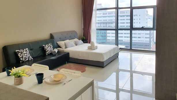 A modern hotel room with a large window, a sofa, a bed, and a dining area with a table and chairs.