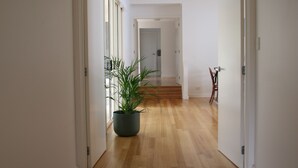 Un pasillo con suelo de madera, una planta en maceta y un sillón.