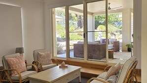 Un salón espacioso con un gran ventanal corredera que da a un patio exterior.