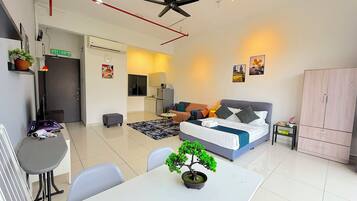 A modern apartment with a dining area, kitchenette, and a bedroom with a bed and seating area.