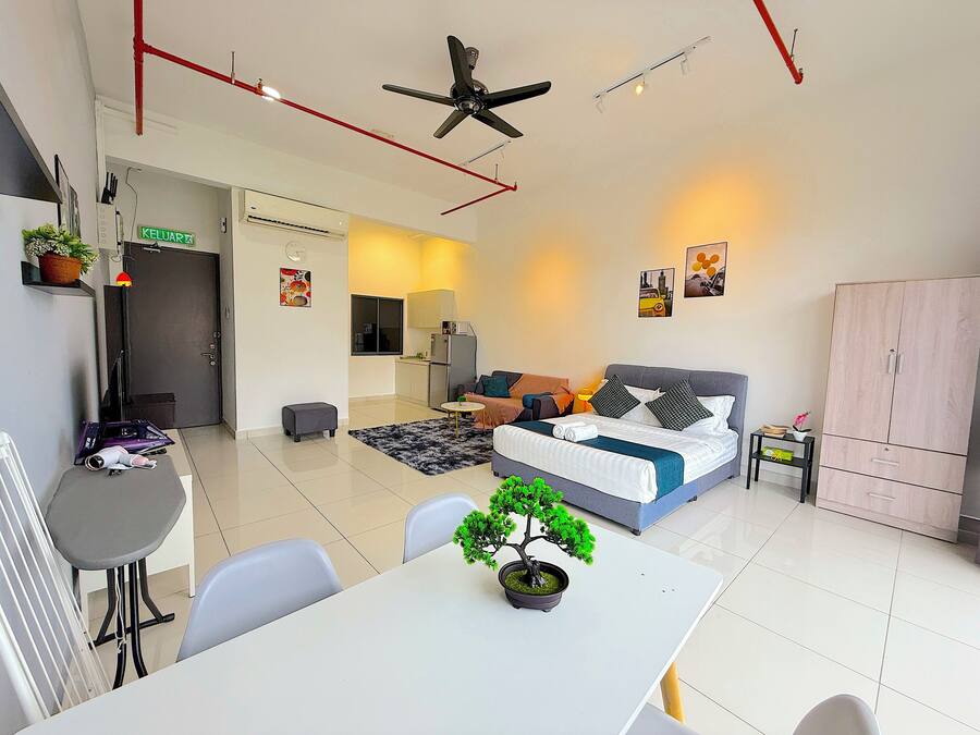 A modern apartment with a dining area, kitchenette, and a bedroom with a bed and seating area.