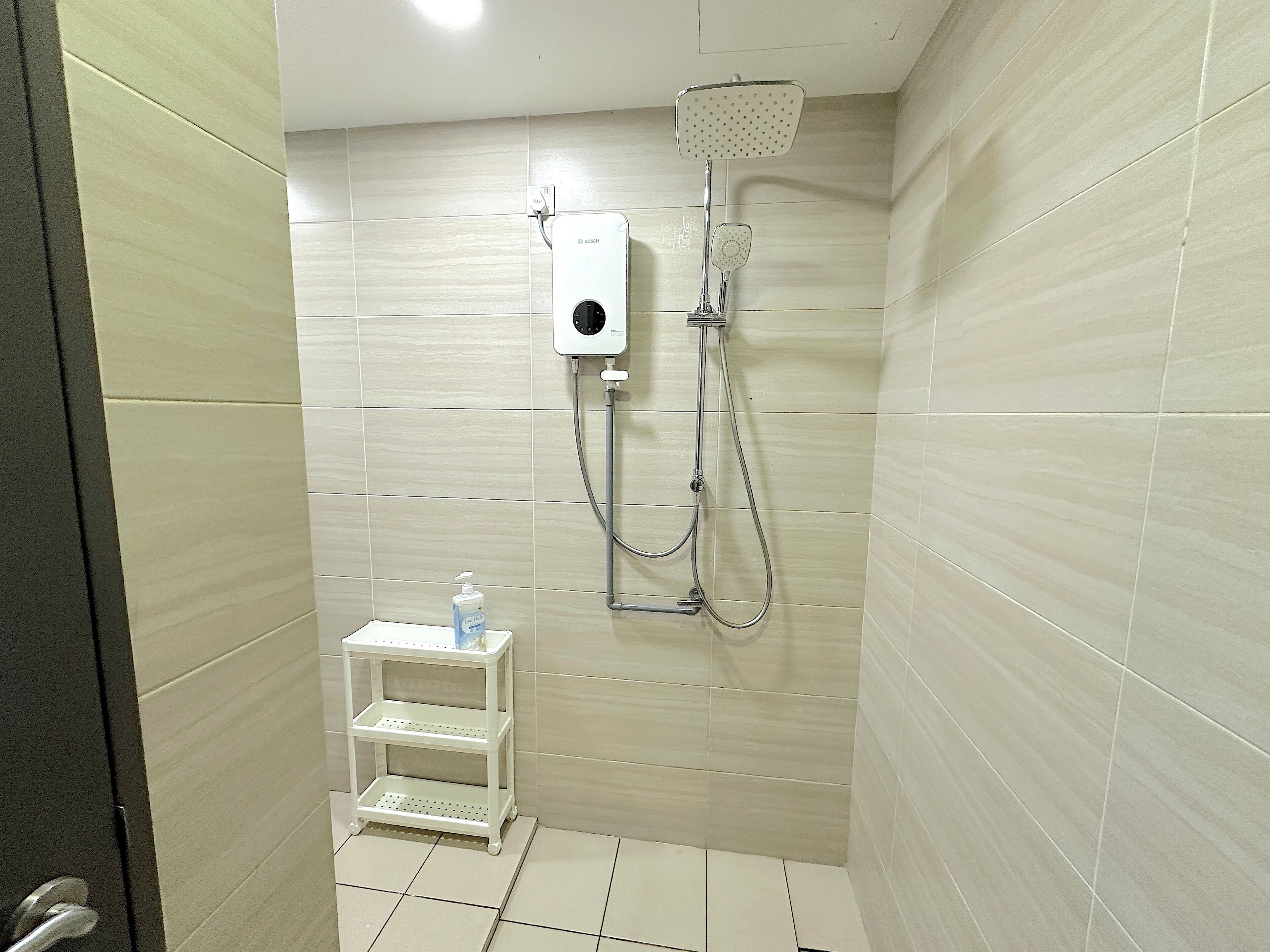 Een badkamer met een douche, een wit kastplankje met toiletartikelen en betegelde muren.