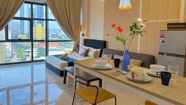 A modern hotel room with a bed, a dining area, and a view of the cityscape. - 3 Towers Jalan Ampang By Serenity Homes (Kuala Lumpur)