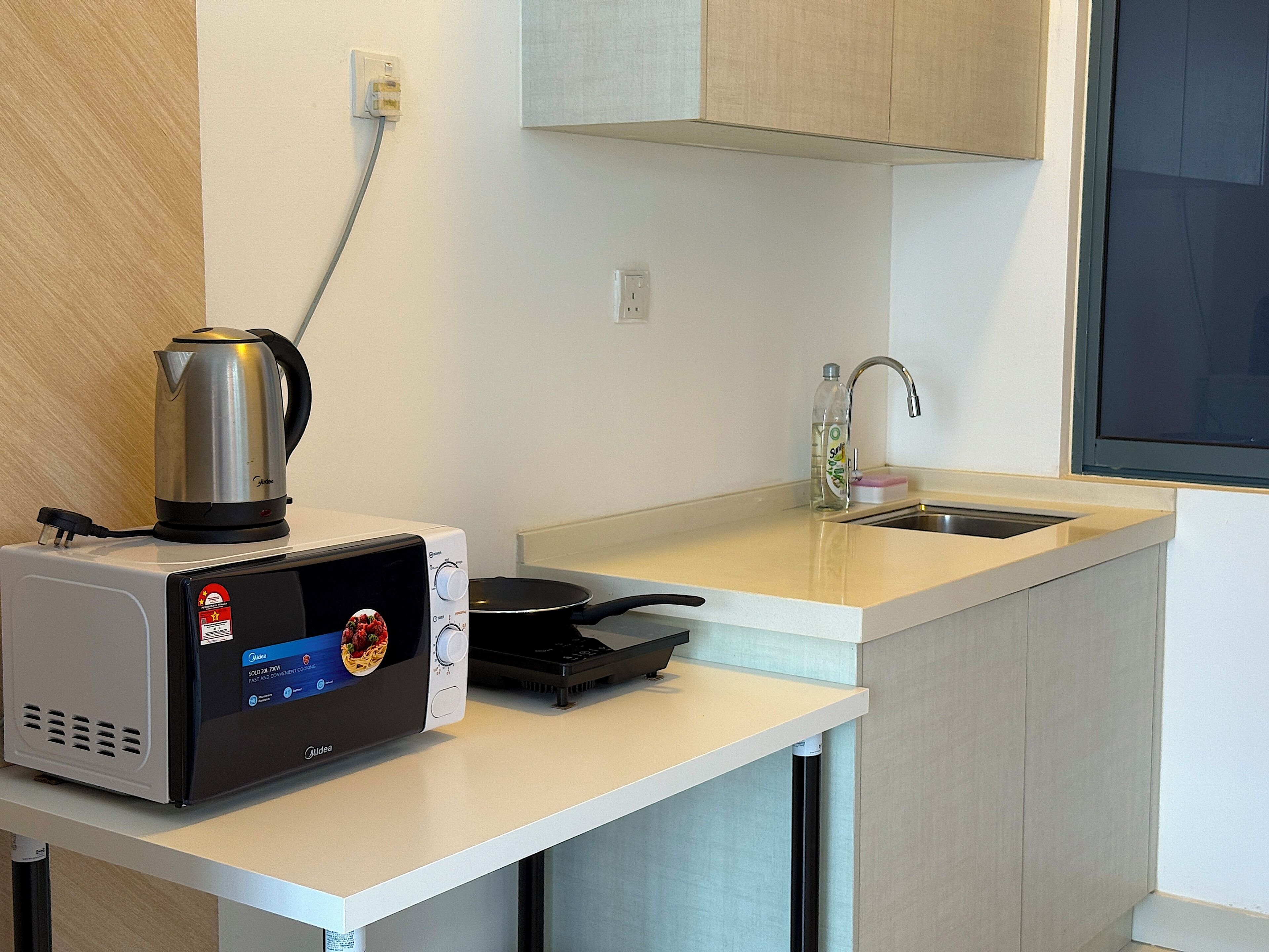 Cocina compacta con microondas, hervidor y fogones pequeños.