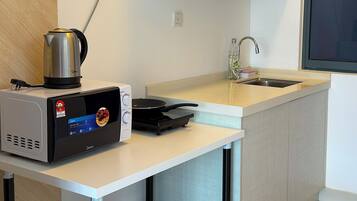 Cocina compacta con microondas, hervidor y fogones pequeños.