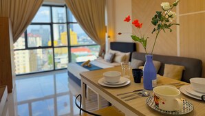 A modern hotel room with a dining area, a bed with a view, and a vase with flowers. - 3 Towers Jalan Ampang By Serenity Homes (Kuala Lumpur)