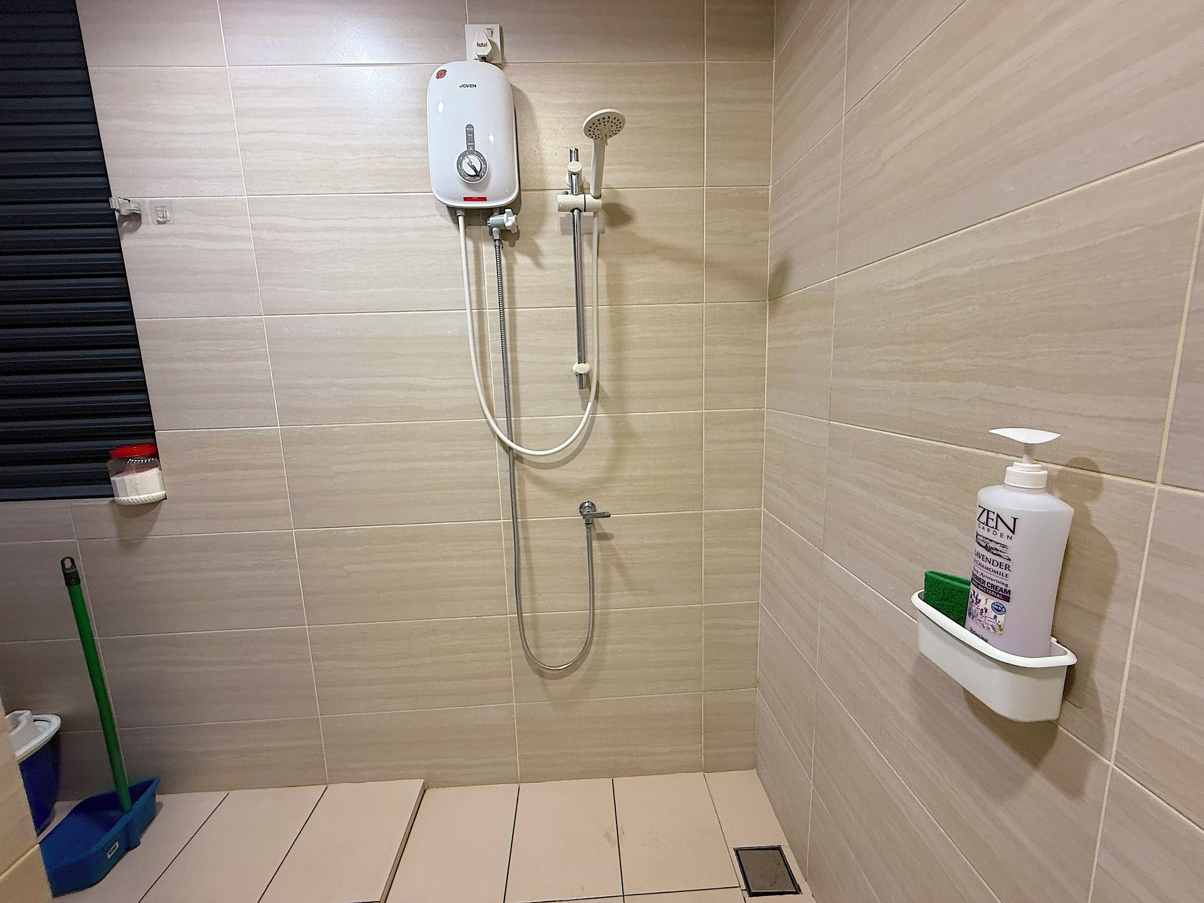 Un baño con ducha, inodoro y estante con artículos de aseo.