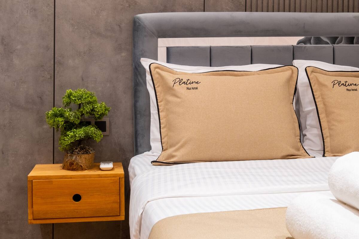 A neatly arranged bedroom with a bed, bedside table, and a wall-mounted light fixture.