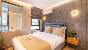 A modern bedroom with a large bed, a bedside table with a plant, and a window with blinds. - The Platine Plus Suite (Istanbul)