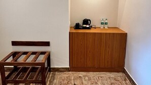 Una habitación pequeña y acogedora con un banco de madera, un armario empotrado de madera y una cafetera sobre la encimera.