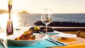 Une table mise pour un repas, avec un verre de vin, une assiette de nourriture et un vase de fleurs.