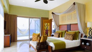 Une chambre spacieuse avec un grand lit, une vue sur la mer grâce à une porte coulissante et un ventilateur de plafond.