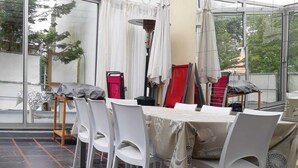 A dining area with a table set for six, surrounded by white chairs. The floor has a black and orange tile pattern. - Villa Classée Face Mer, Petit Jardin , Veranda et Terrasse Ensoleillée, 120 m2, (La Baule-Escoublac)