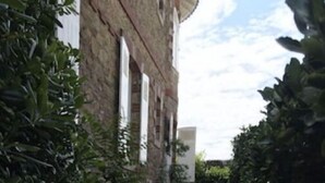 A narrow stone pathway leading to a building with a brick facade and white window frames. - Villa Classée Face Mer, Petit Jardin , Veranda et Terrasse Ensoleillée, 120 m2, (La Baule-Escoublac)
