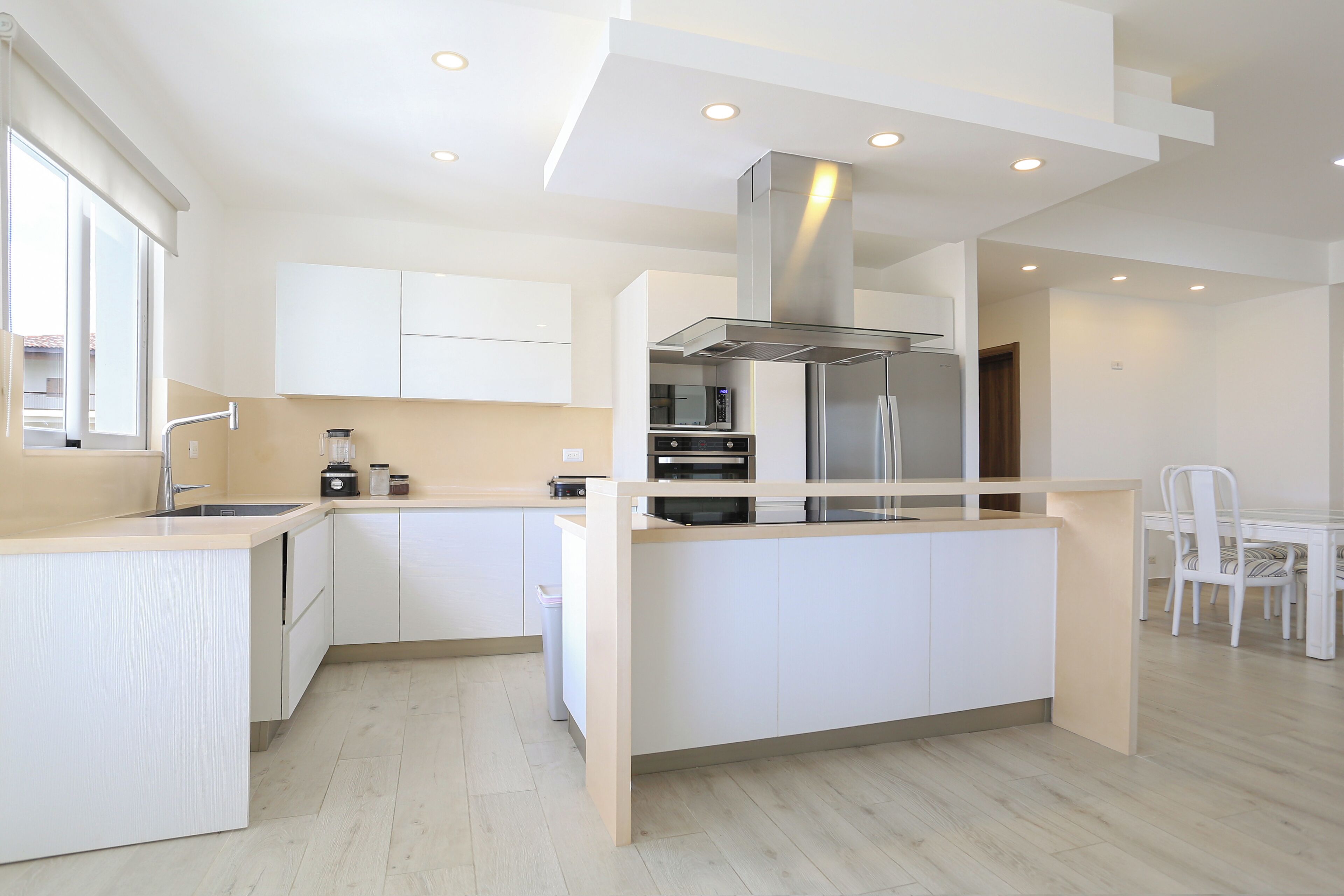Een moderne keuken met witte kasten, een centraal eiland en ingebouwde apparatuur.