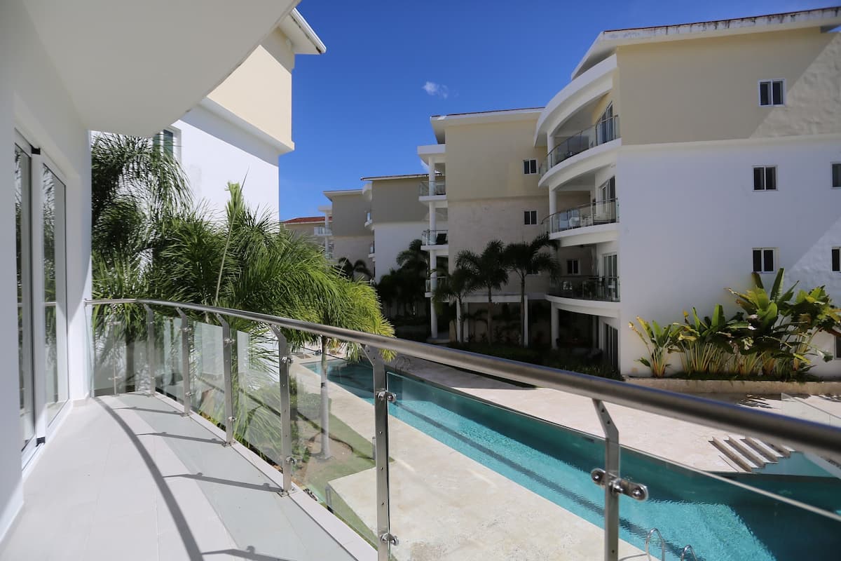 Un hôtel moderne doté d’une piscine, de garde-corps en verre et de nombreux balcons.