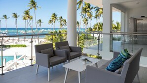 Un balcon avec vue sur la plage et l’océan, aménagé avec des chaises et une table.