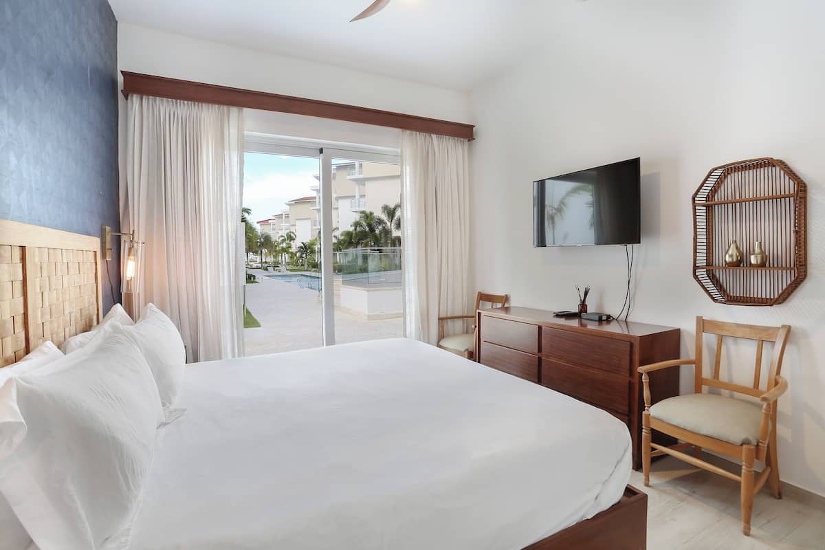 Une chambre d’hôtel avec un grand lit, un bureau avec une chaise, une télévision et une vue sur l’extérieur.