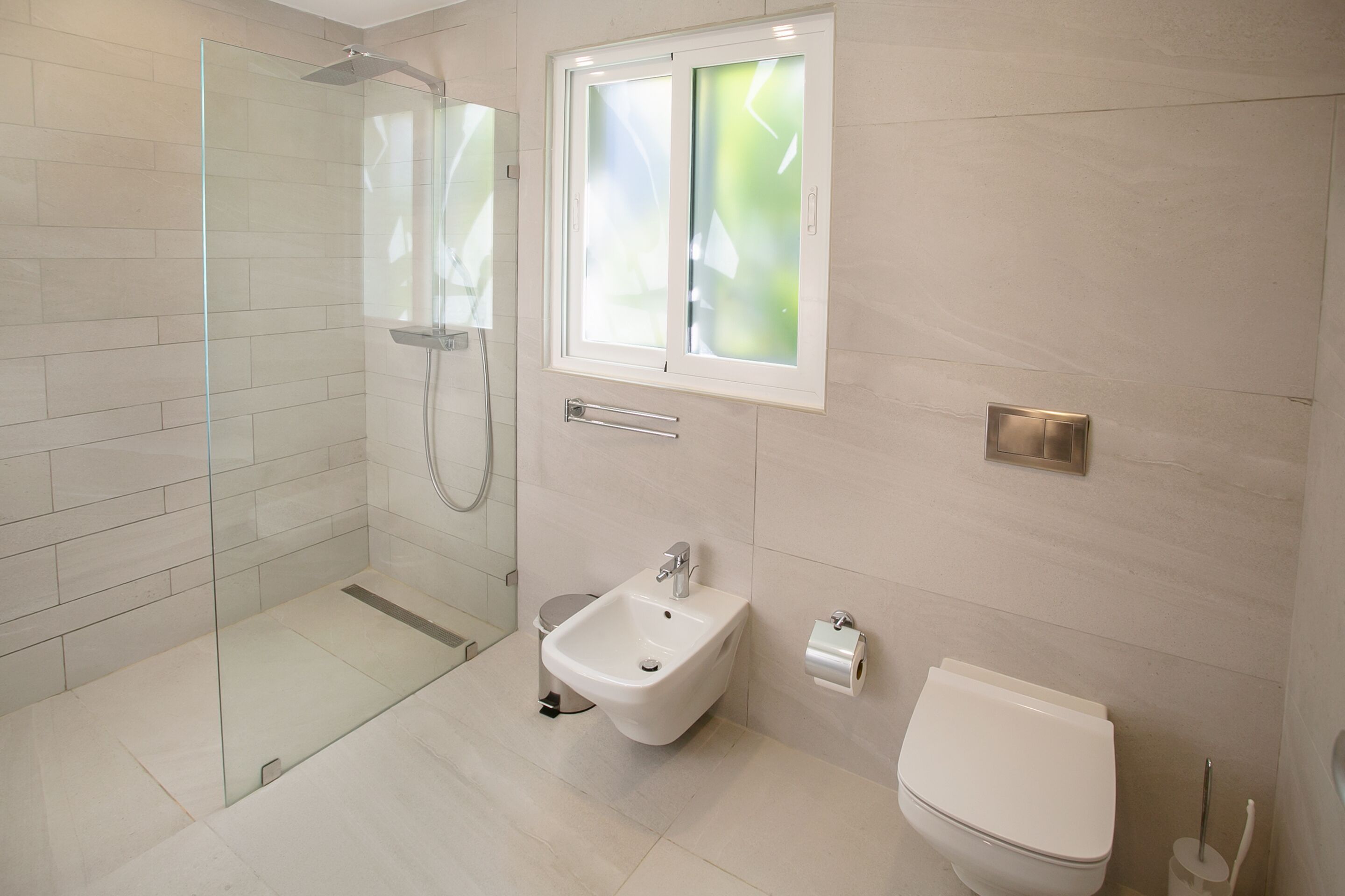 Une salle de bain moderne dotée d’une douche à parois de verre, d’un bidet et de toilettes.
