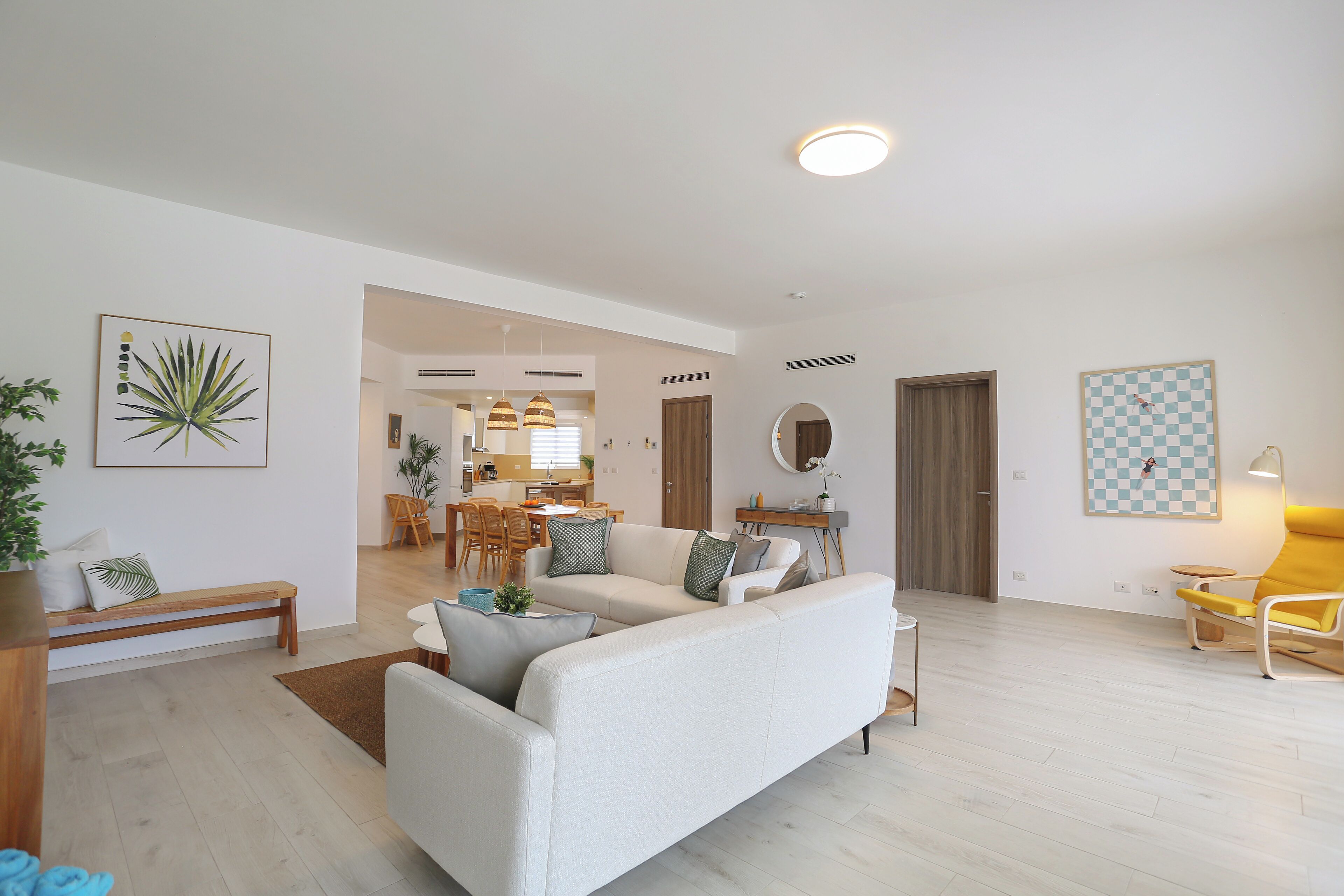 Un salon moderne avec un canapé, un coin repas et une cuisine en arrière-plan.
