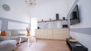 A modern living room with a sofa, a coffee table, and a TV mounted on the wall. - Venus Apartments - Klauzál Apartment (Budapest)