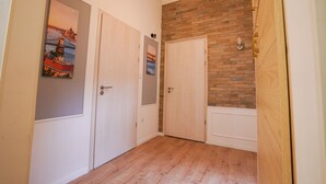 A hallway with two white doors, a brick accent wall, and a wooden floor. - Venus Apartments - Klauzál Apartment (Budapest)