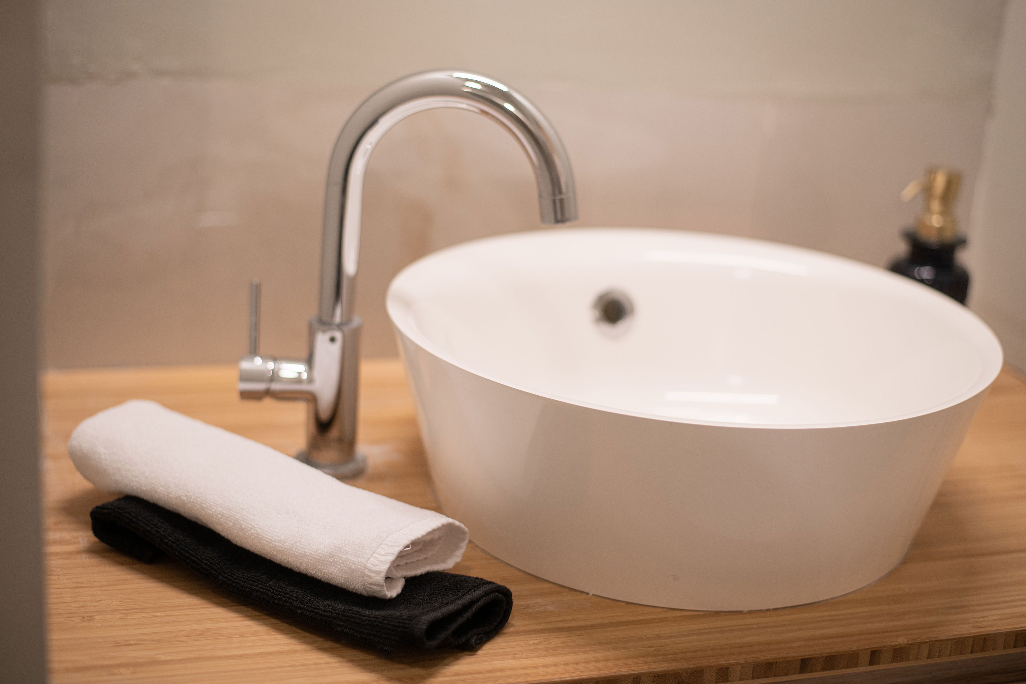 A bathroom with a white sink, a faucet, and a towel on a wooden countertop.