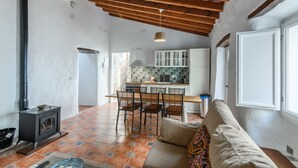 Una sala de estar acogedora con chimenea, un comedor con sillas y una cocina con armarios.