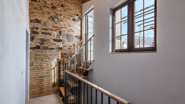Una escalera con un muro de piedra a un lado y una ventana al otro.