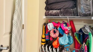 A storage closet with shelves holding various items including bags, umbrellas, and sports equipment. - Direct Oceanfront View with KingBed+Pools +GarageParking+Gym+InUnitWasher&Dryer (Myrtle Beach)
