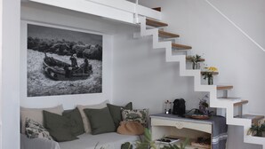A modern living room with a sofa, a coffee table, a bookshelf, and a staircase with wooden steps. - My Place Your Place - Corniglia, 5 Terre (Vernazza, Corniglia)