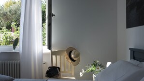 A bedroom with a bed, a chair, a hat on the wall, and a window with curtains. - My Place Your Place - Corniglia, 5 Terre (Vernazza, Corniglia)