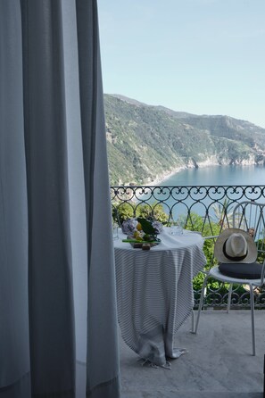 A balcony with a table set for two, overlooking a coastal landscape.