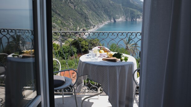 A balcony with a table set for a meal, overlooking a coastal landscape. - My Place Your Place - Corniglia, 5 Terre (Vernazza, Corniglia)