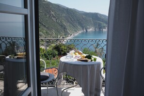 A balcony with a table set for a meal, overlooking a coastal landscape. - My Place Your Place - Corniglia, 5 Terre (Vernazza, Corniglia)