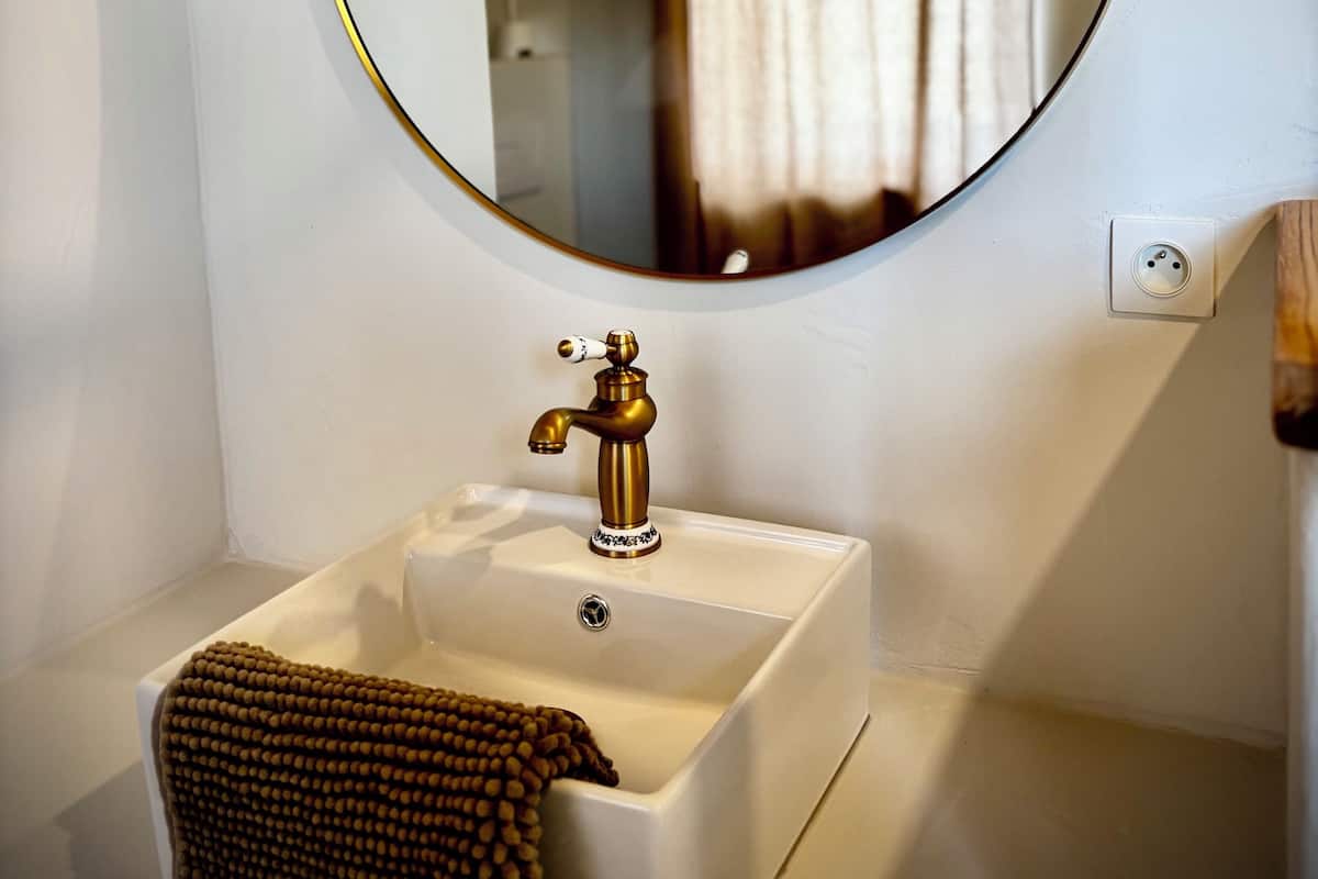 A bathroom with a round mirror, a sink, and a towel.