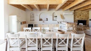 Una cocina moderna con armarios blancos, vigas de madera y pared de piedra.