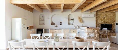 Una cocina moderna con armarios blancos, vigas de madera y pared de piedra.