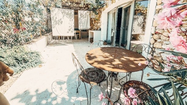 Un patio al aire libre con un edificio de piedra, una mesa redonda y sillas.
