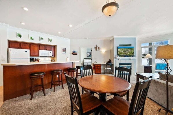 A modern kitchen with a central island, bar stools, and a dining area with a round table and chairs. - Horseshoe Bay #1-Private Golf Club Access! (Egg Harbor)