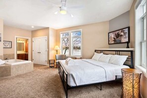 A bedroom with a bed, a bedside table, a lamp, a chair, a window, and a painting on the wall. - Horseshoe Bay #1-Private Golf Club Access! (Egg Harbor)