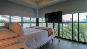 Camera da letto moderna con un letto grande, una TV a schermo piatto montata a parete e vista sulla città attraverso ampie finestre.