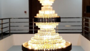 Un candelabro de varios niveles en una habitación amplia con suelo de madera y paredes blancas.