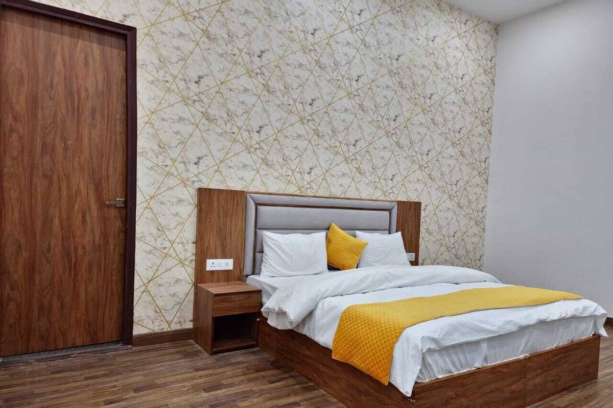 Un dormitorio con cama de madera, ropa de cama blanca y un edredón amarillo.