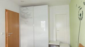 Quarto com cama, guarda-roupa, escrivaninha e porta.