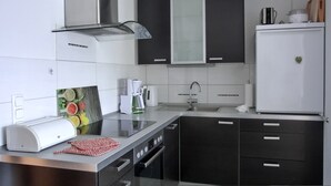 Cozinha moderna com armários pretos e brancos, coifa de aço inoxidável, cafeteira e geladeira.